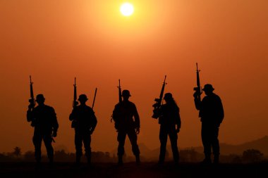 Gün batımında silahlı asker ya da subay silueti. Ateş edildi, silah tutuldu, renkli bir gökyüzünde dikildi, akşamları günbatımının arka planı 