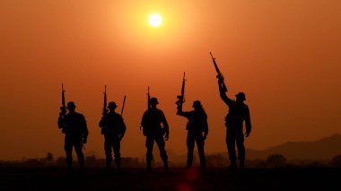 Gün batımında silahlı asker ya da subay silueti. Ateş edildi, silah tutuldu, renkli bir gökyüzünde dikildi, akşamları günbatımının arka planı 