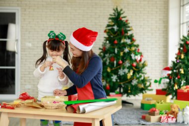 Asyalı anne ve kızı evdeki Noel ağacı etkinliklerinde birbirlerine yardım ediyorlar.