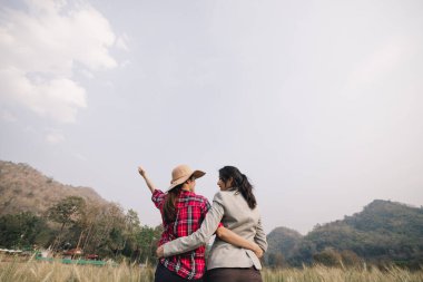 Çiftçi ve iş kadını arpa tarlasında ve gökyüzü arka planında sarılıp el kaldırıyor.