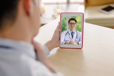 Doktor adam ebeveynlerine danışmanlık yapıyor. Video konferans sistemi, masadaki tabletteki kablosuz teknoloji iletişimi ve seçici odaklanma yoluyla. 