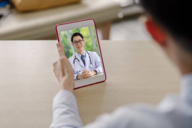 Doktor adam ebeveynlerine danışmanlık yapıyor. Video konferans sistemi, masadaki tabletteki kablosuz teknoloji iletişimi ve seçici odaklanma yoluyla. 