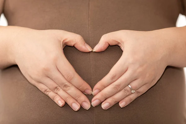 hand made women asian are heart shaped on the pregnant belly mother loves care baby concept close up to selective focus