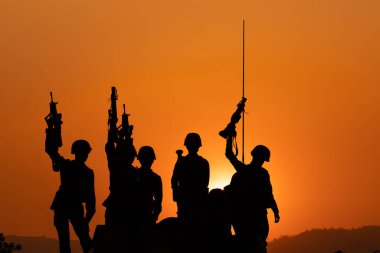 Siluet ve gündoğumunda arka planda top askerler Tayland 'da silah tutuyorlar.