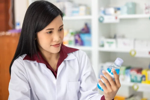 Молодой Азиатский Фармацевт Ищет Бутылку Синего Геля Рукой Аптеке Таиланда — стоковое фото