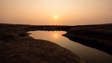 Sabah sahnesinde güneş ışığı ve büyük kanyon Sam Phan Bok Ubon Ratchathani Thailan 'daki su cephesinde küçük turist yansıması.