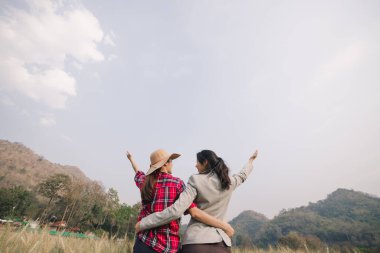 Çiftçi ve iş kadını arpa tarlasında ve gökyüzü arka planında sarılıp el kaldırıyor.