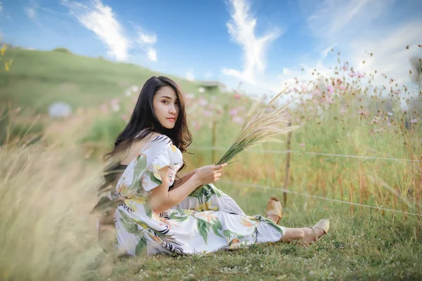 아름다운 동양인 여인들은 미소를 풀꽃을 앉아서 편안하게 있습니다 — 스톡 사진