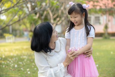 Taylandlı emekli kadın yeğen bahçede mutlu mesut konuşuyor ve gülümsüyor.