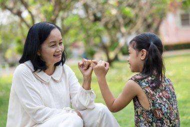 Büyükanne ve torun bahçede el ele oturuyorlar. Tayland 'da mutlu aile emekliliği kavramı.