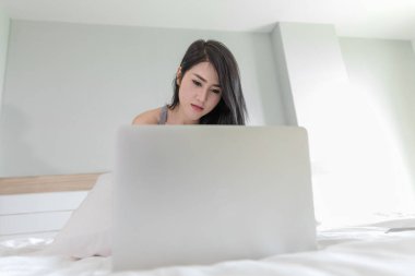 Yatak odasındaki beyaz dizüstü bilgisayar kullanan kadın yumuşak spor odaklı.