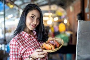 Elinde bambu kabında yengeç var. Amphawa su pazarında genç bir turist. Tayland 'da.