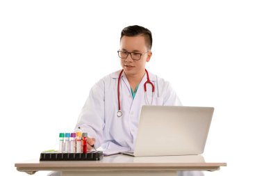 Masanın üzerinde kan örneği ve dizüstü bilgisayarı olan Taylandlı bir doktor.