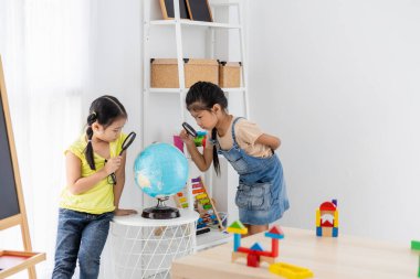 Asyalı öğrenciler, okula dönüş konseptine bakmak için büyüteç kullanıyorlar.