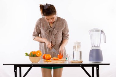 Kız portakal, meyve suyu, meyve blender, kovan sürahiler ve beyaz arka plan ışık stüdyosu olan ahşap kaplar gibi malzemelerle meyve suyu yapmayı öğreniyordu.