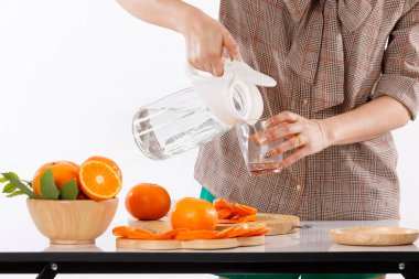 Kız portakal, meyve suyu, meyve blender, kovan sürahiler ve beyaz arka plan ışık stüdyosu olan ahşap kaplar gibi malzemelerle meyve suyu yapmayı öğreniyordu.