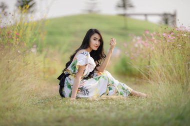 Güzel Asyalı kadınların portresi mutlu bir gülümseme ve rahatlama ile çiçek bahçesinde oturuyor; dağ gibi berrak. Gökyüzü geçmişi, Tayland 'da yalnız doğa insanları kavramı