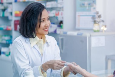 Tayland eczanesindeki hastaya el reçetesi yazan kadın doktor. 