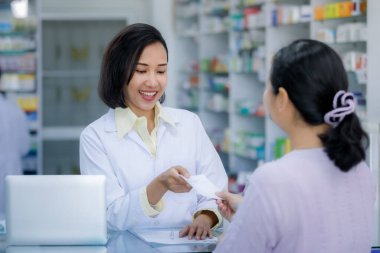 Tayland eczanesindeki hastaya el reçetesi yazan kadın doktor. 