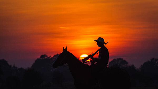 landscape silhouette cowboy horse carrying riding a gun the backdrop is the sun
