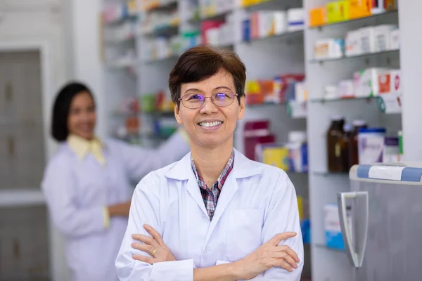 Phamacist Femminile Piedi Abbracciando Sorridente Farmacia Con Uno Scaffale Persone — Foto Stock