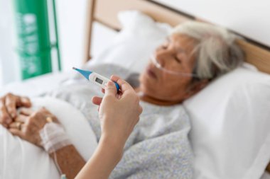 Asyalı hemşire yaşlı hastalara termometre cıva kullanır