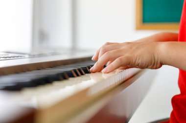 Sınıfta piyano çalan Asyalı çocuk seçici odak noktasını kapatıyor.