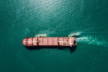 red oil ship tank and tugboat sailing on green sea photograph aerial from drone point of view 
