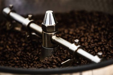 Taze kahve çekirdekleri ve kavrulmuş döner düdüklü profesyonel makine. Fotoğraf bulanıklığını kapat ve Chiang Rai Tayland fabrikasının arka planını karart.