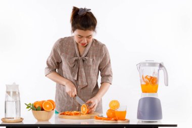 Kız portakal, meyve suyu, meyve blender, kovan sürahiler ve beyaz arka plan ışık stüdyosu olan ahşap kaplar gibi malzemelerle meyve suyu yapmayı öğreniyordu.
