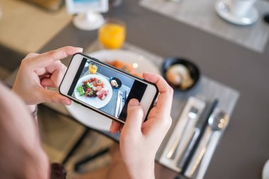 Kız akıllı telefon kamerasıyla yemek salatası fotoğrafı çekiyor. Spor odaklarına yakın çekim yapıyor.