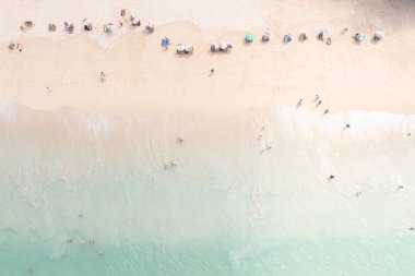 Hava manzaralı küçük insanlar tatil ve şemsiye üzerinde denizde oynayan turistler yaz tatili konsepti. 