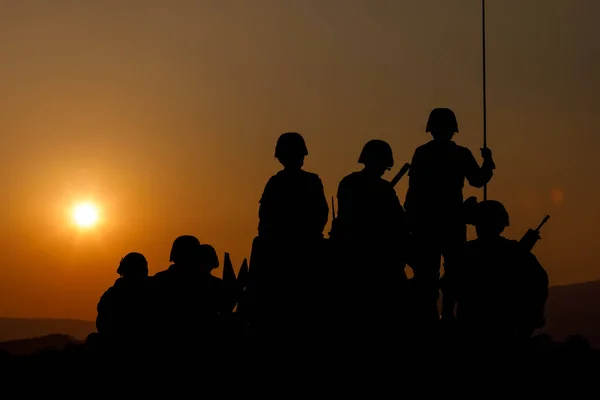 特殊部隊のシルエットグループ兵士たちが日没の背景に戦車に座り — ストック写真