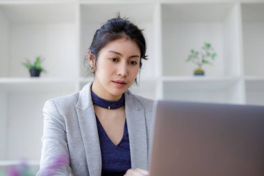 Laptop bilgisayar kullanan genç Asyalı güzel bir kadın, modern ofisinde oturuyor ve sosyal ağda mesaj yazarak sohbet ediyor. Konsept, Onlin 'de çalışan blogger serbest yazarına odaklanmış durumda.