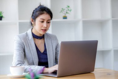 Laptop bilgisayar kullanan genç Asyalı güzel bir kadın, modern ofisinde oturuyor ve sosyal ağda mesaj yazarak sohbet ediyor. Konsept, Onlin 'de çalışan blogger serbest yazarına odaklanmış durumda.