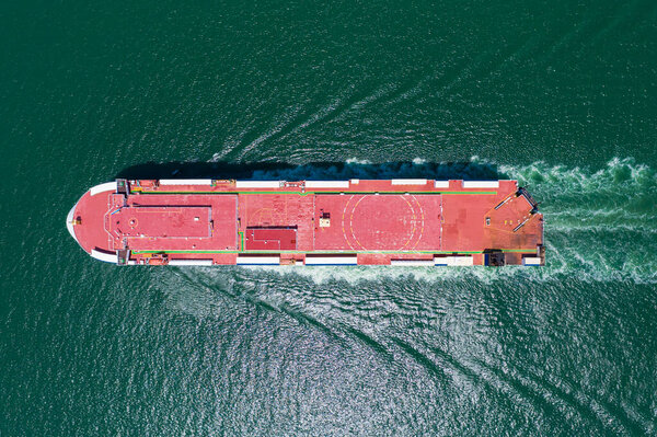 Car carrier shipping out trade port green sea. Aerial top view.