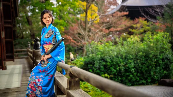 日本秋天 身穿日本蓝色和服和雨伞的亚洲女人手牵手站在公园里的肖像 — 图库照片