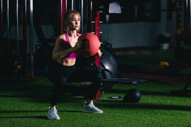 Pembe spor kıyafetli Asyalı kadın spor salonunda kettlebell egzersizi yapıyor. 