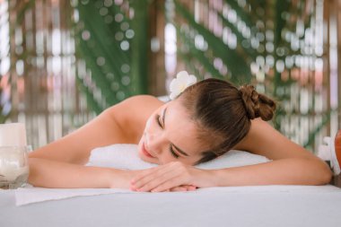Güzel, genç Asyalı bir kadın masaj salonunda dinlenerek uyuyor. Kapat ve odaklanmış doğal ışık arkaplanını seç 