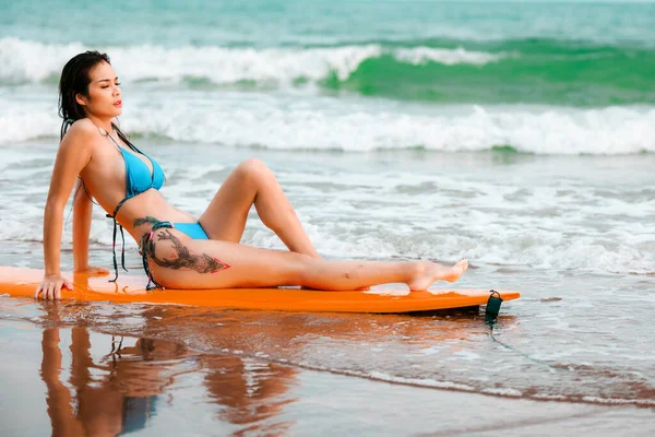 美丽的亚洲女孩穿着比基尼坐在冲浪板上 在热带的沙滩上摆姿势 在海上度过暑假 — 图库照片