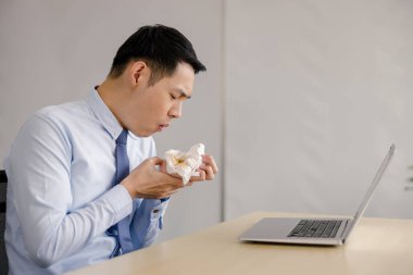 Genç Asyalı iş adamı video danışmanı öksürdükten sonra eline gastrointestinal hastalığı olduğundan şüphelenilen ve muhtemelen hayatını tehdit eden bir şey kustuktan sonra doktora danışıyor., 