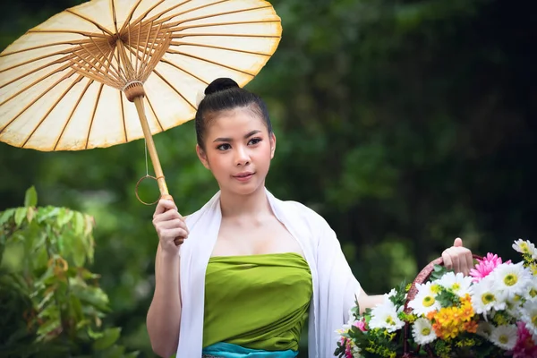 在泰国北部 年轻的亚洲女孩穿着当地的衣服 带着雨伞 绿色的公园里开着花 — 图库照片