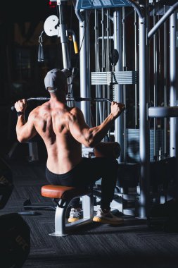Fitness white ethnicity man working out in gym doing exercise focusing on the muscles arms and shoulders cinematic dark tone, healthy style concept 