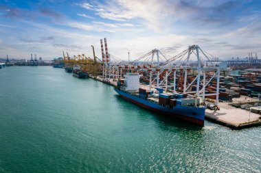 Konteynırlar ticari nakliye limanı ve konteynır gemisi vinç küresel ticaret ve endüstri hizmetleri yükleme dünya çapında ithalat ihracat ihracat deniz manzaralı İHA mavi gökyüzü arka planından uluslararası,