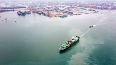 Uluslararası ve dünya çapında ithalat için konteynırlarda mal taşımak üzere yelken açan konteyner gemisi, konteyner gemisi açık denizle iş hizmetleri taşımacılığı, insansız hava aracı görüntüsü, ticari liman arka planı