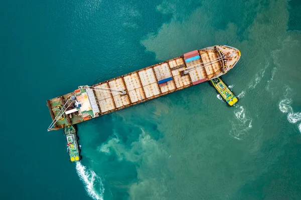 航空機のトップビュー商業港へのコンテナ船を押すタグボート貨物コンテナのロードと積み降ろし緑の海での国際的なインポートタイ — ストック写真