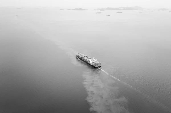 black and white cargo container ship full speed sailing in sea import and export business and industry logistic goods transportation of international by container ship in ocean fright aerial view photograph from drone