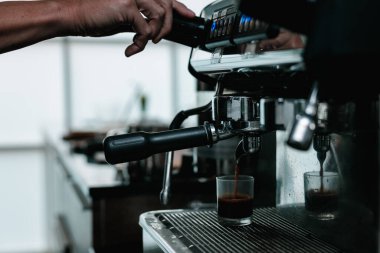 asian man bartender mixing and pouring coffee into cup from coffee machine at counter in small coffee shop business stratup concept, cinema film tone process