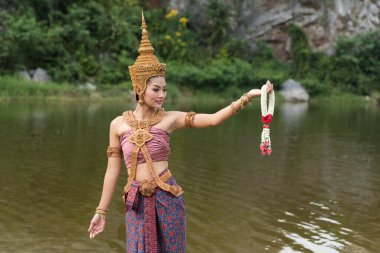 Tayland 'da güzel bir kadın. Geleneksel çelenkler takıyor. Bahçede gülümsüyor.