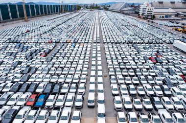 Rows of a new cars automotive line up products parked in warehouse of  factory for distribution dealers trading in import export, aerial view